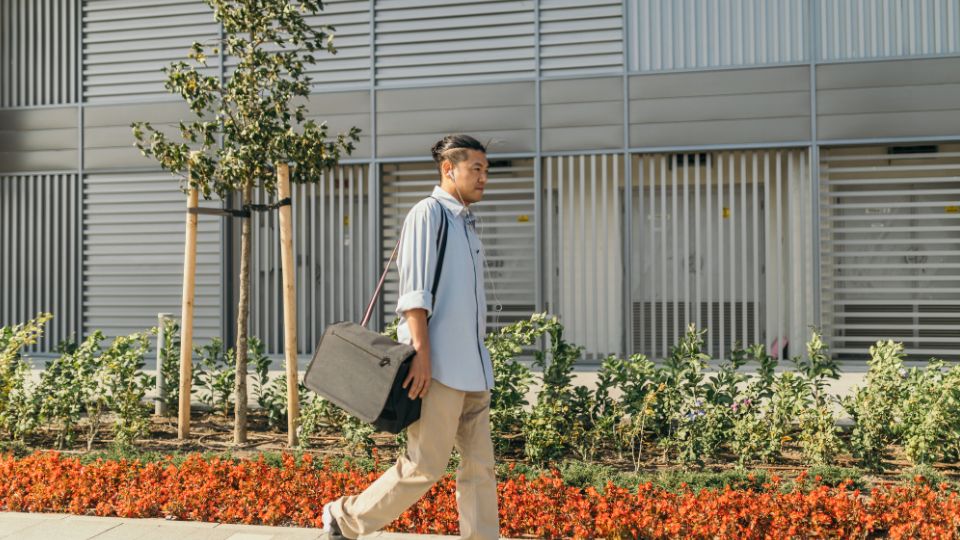 Man loopt buiten met tas — bewegen tijdens of na een zittende werkdag helpt de gezondheidsrisico's te verminderen